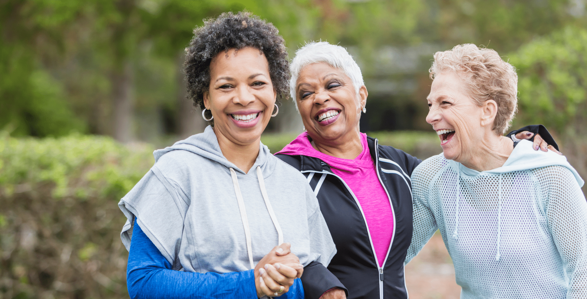 Three older women smiling and laughing outside.