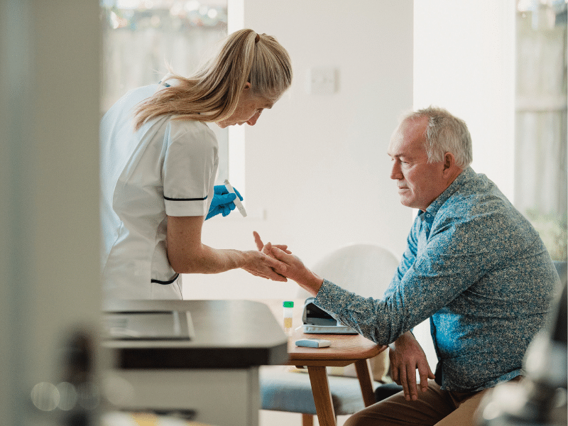 A nurse pricking a mans finger to test blood glucose.