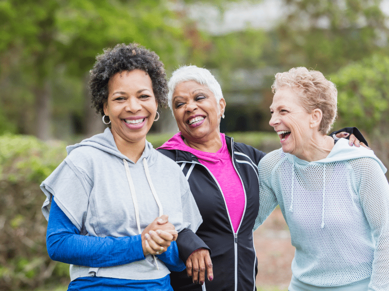 Three older women laughing together outside