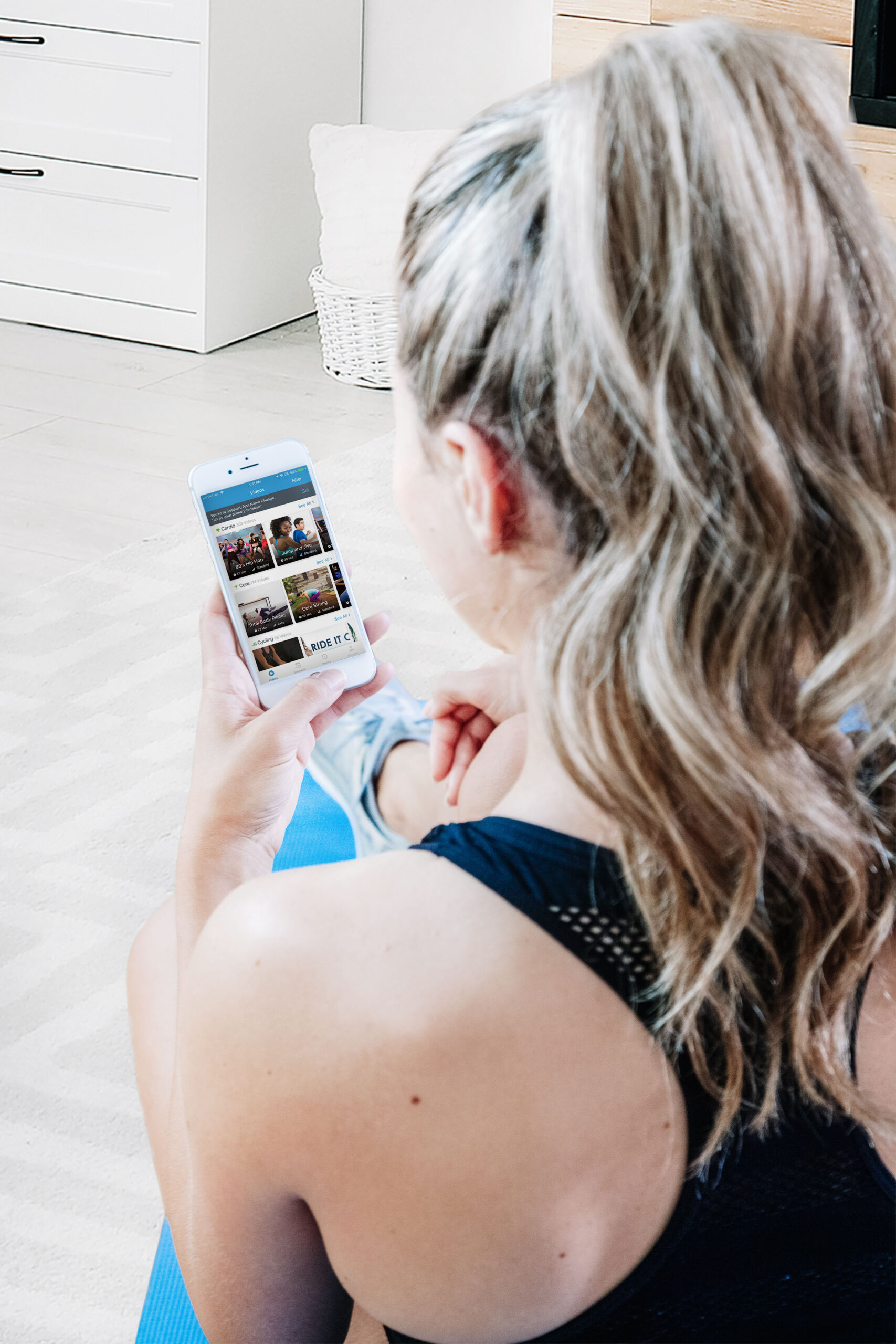 A woman looking at the FLEX Fitness on Demand app on her phone.