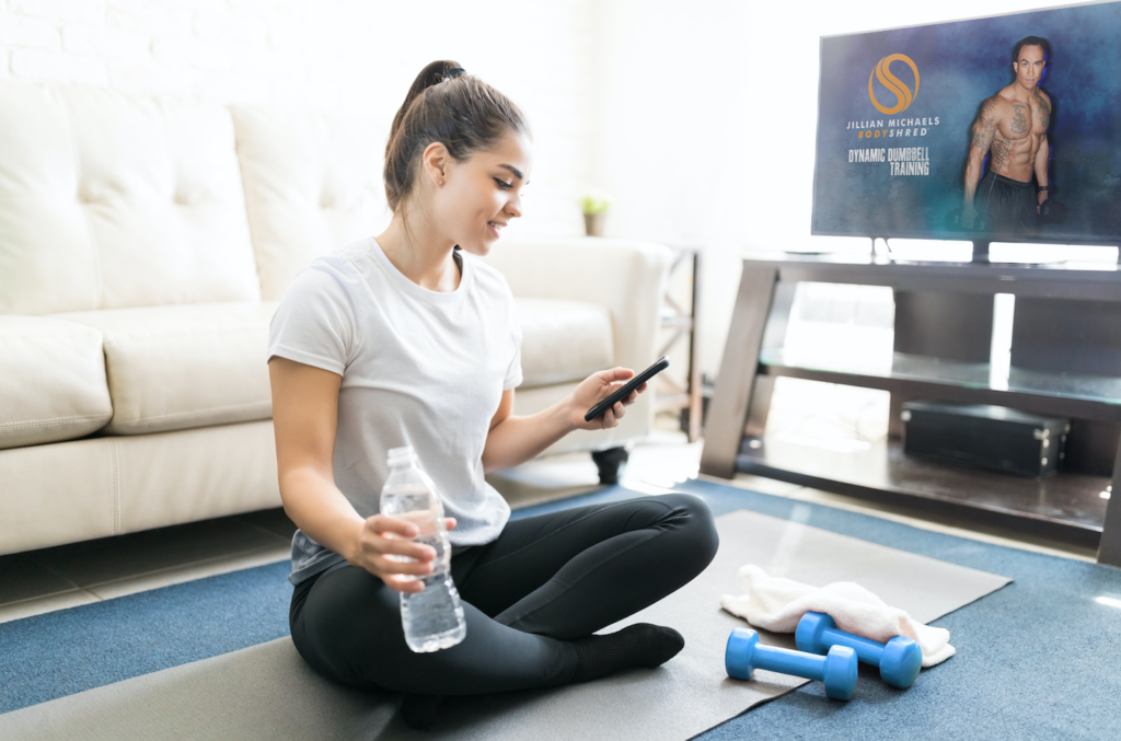 A person looking at their phone after using the FLEX fitness on Demand app to workout.