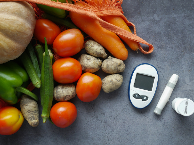 Healthy veggies next to diabetes supplies.