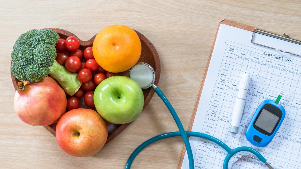 A bowl of fruits and vegetables with a blood glucose monitor.