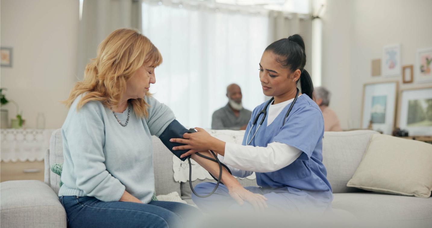 A woman getting her blood pressure taken by a nurse.